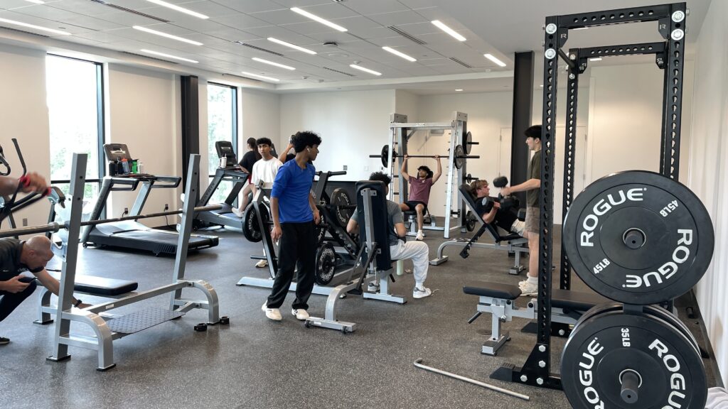 Students in NCSSM-Morganton’s new weight room move about the room as they make use of the weight-lifting equipment. (photo: Emily Cunard)